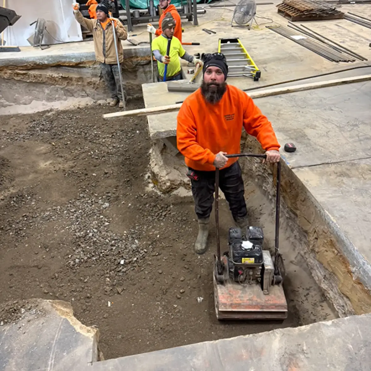 Worker compacting the stone subbase before an interior concrete floor pour in Cherry Hill, NJ