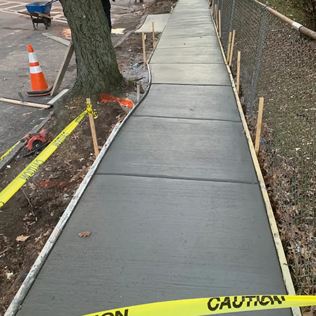 Caution tape and a cone protecting a freshly poured concrete sidewalk in Cherry Hill, New Jersey