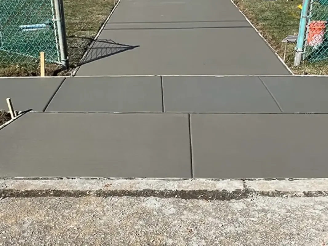 Edge of a new concrete driveway slab where it meets the older curb line in Cherry Hill, New Jersey