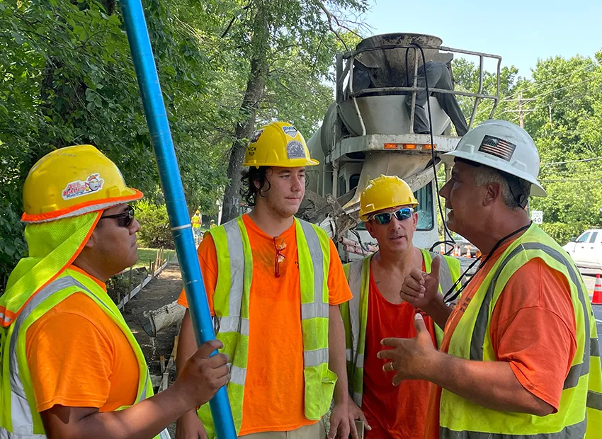 Concrete crew in hard hats and safety vests planning a pour beside a mixer truck, serving homes in Echelon, NJ