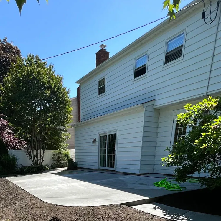 New concrete patio beside a white two-story home with shrubs and trees, the kind of backyard found in Gibbsboro, NJ