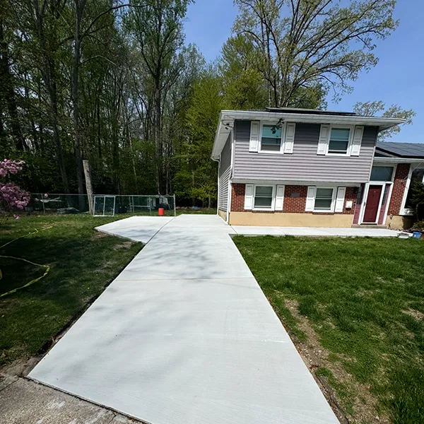 New concrete driveway leading to a split-level home with a wide lawn, work by an Osage, NJ concrete contractor