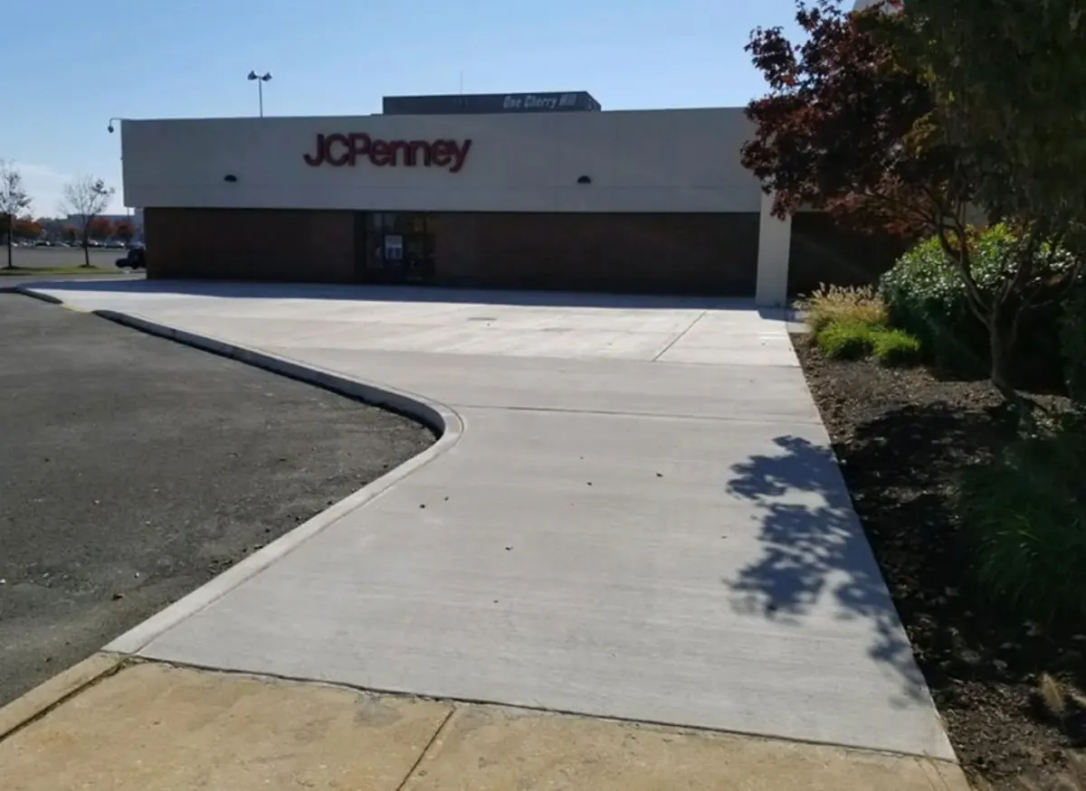 Finished concrete paving at a retail store entrance next to the customer parking area