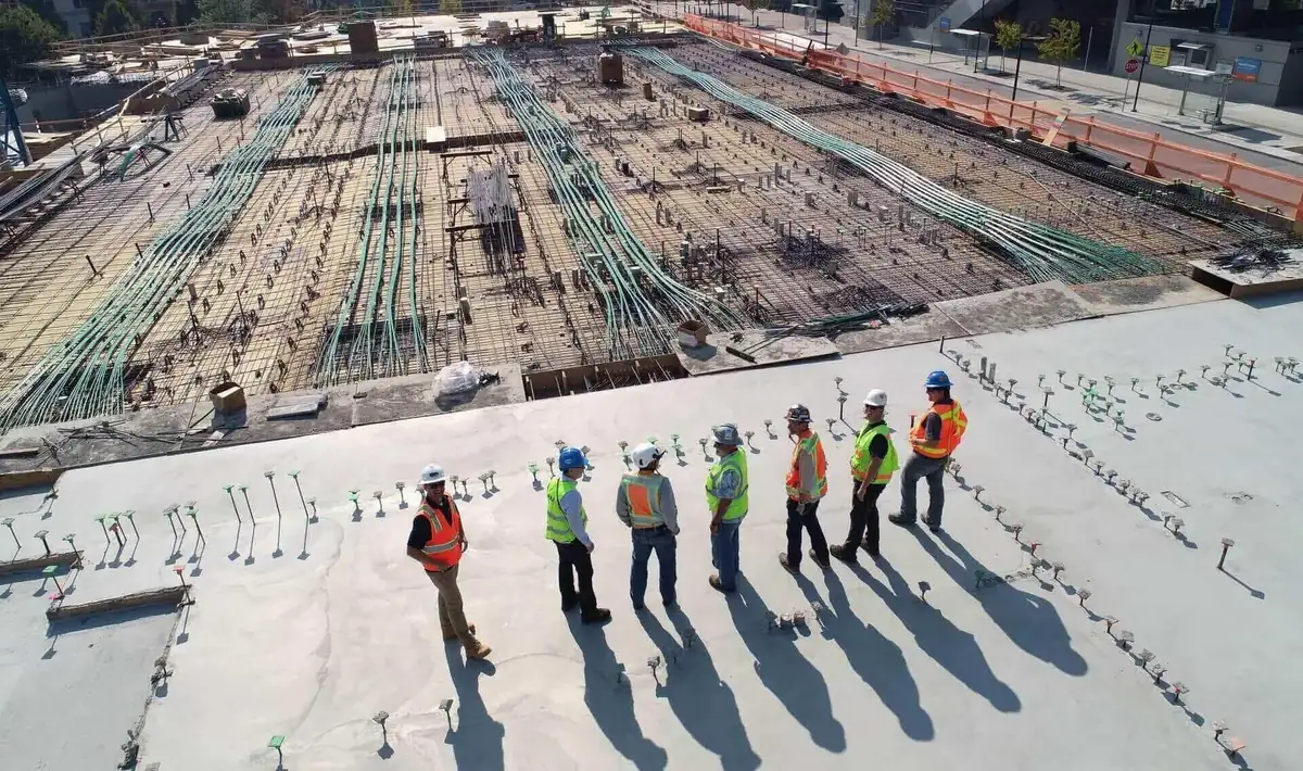 Aerial view of a large commercial concrete slab pour with reinforcing steel and a full crew working the pad