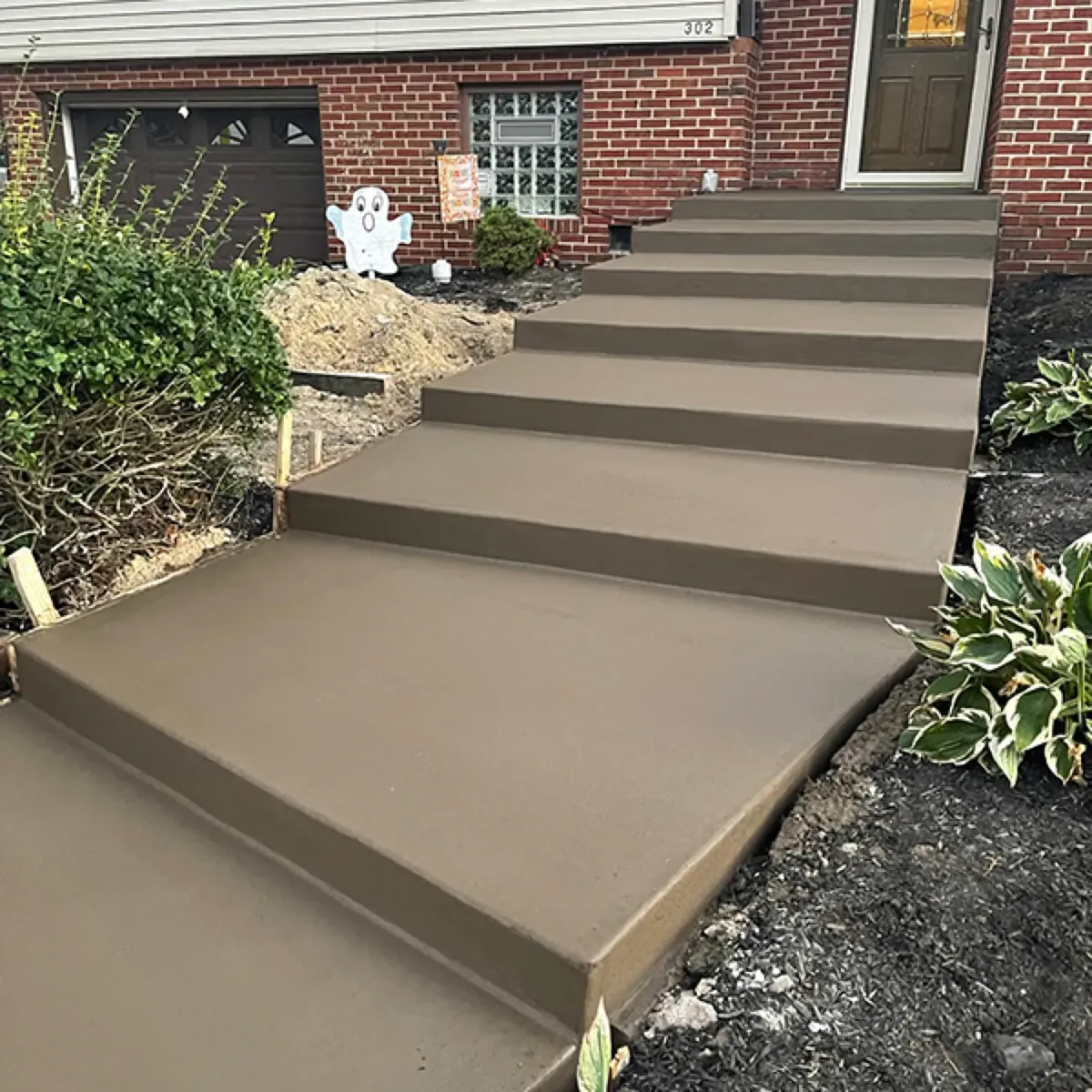 Rebuilt concrete front steps with a wide landing leading to the door of a brick home
