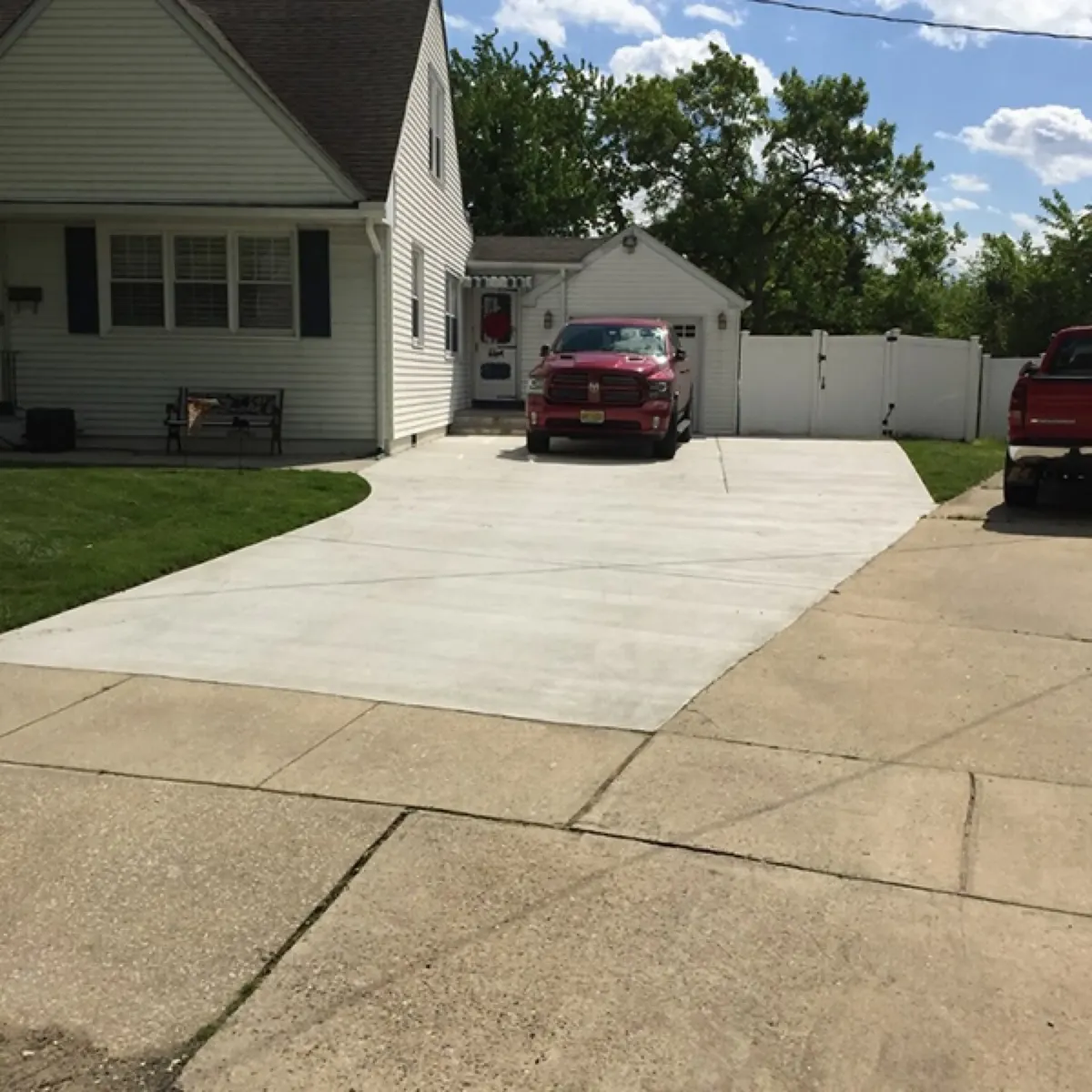Widened concrete driveway beside a home with a pickup truck parked at the top near the fence