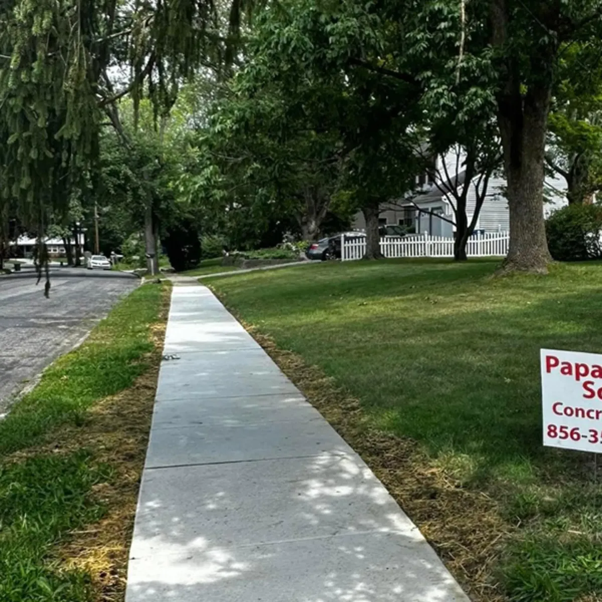 Long new concrete sidewalk running beside a lawn in a South Jersey neighborhood with a Papaneri & Sons yard sign