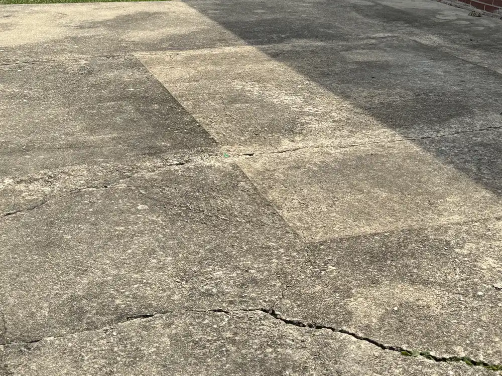 Cracked and worn concrete driveway slab beside a Cherry Hill, NJ home before repair