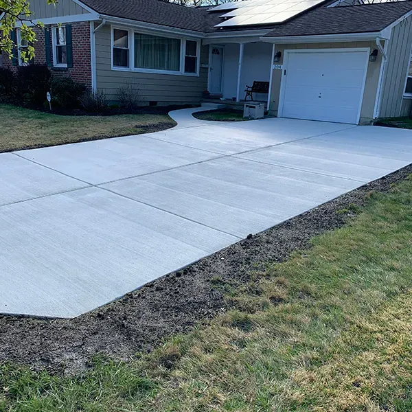 Newly replaced concrete driveway running from the street to an attached garage at a single-story home