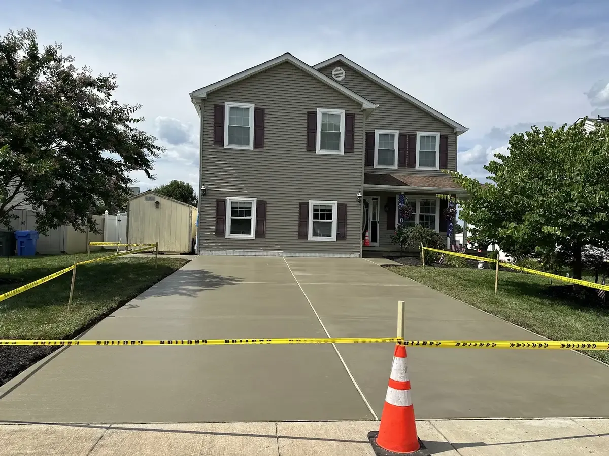 Cones and caution tape protecting a new concrete driveway pour at a South Jersey home