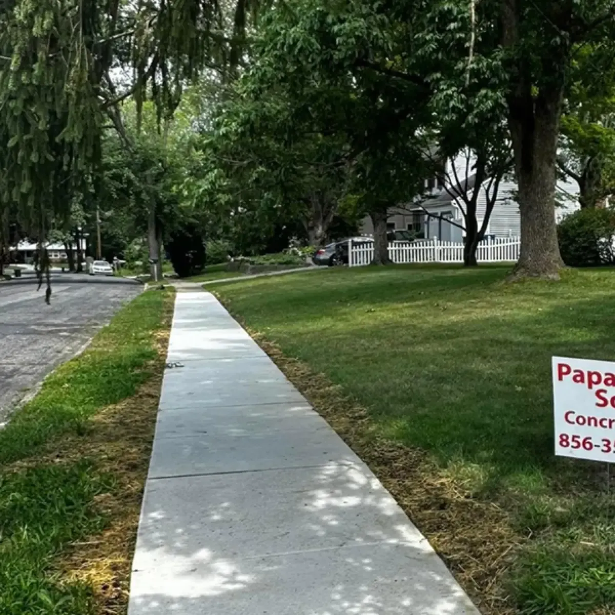 Long new concrete sidewalk running past front lawns on a residential street in Cherry Hill, New Jersey